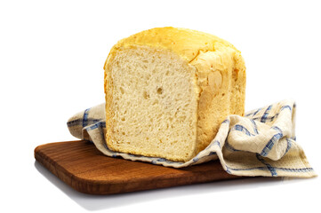 Fresh white wheat homemade bread on a wooden board, covered with a towel, isolate. Homemade cakes, pastries