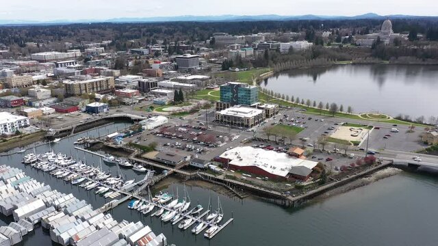 Cinematic drone footage of the Olympia Yacht Club, Capitol Lake Park, Heritage Park, springtime cherry blossoms at the State Capitol with panoramic view of the Historic District in Olympia, Washington