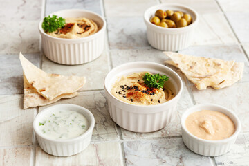 Bowl of hummus, traditional Jewish, Arabian, Middle Eastern food from chick-peas with deeps and with  pita flatbread on ceramic tile background. Close up, selective focus