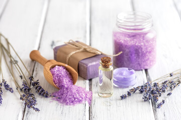 Obraz na płótnie Canvas Lavender spa products on an old white wooden table. Body care products with lavender-oil, salt, cream, soap and dried lavender flowers. Selective focus.