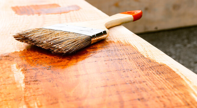 Painting wood with a brush and paint and varnish materials in an open area. Small business, woodworking.