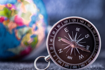 Fototapeta na wymiar Travel planning navigation concept. Classic magnetic detail of compass on light blue with earth globe in the backround.