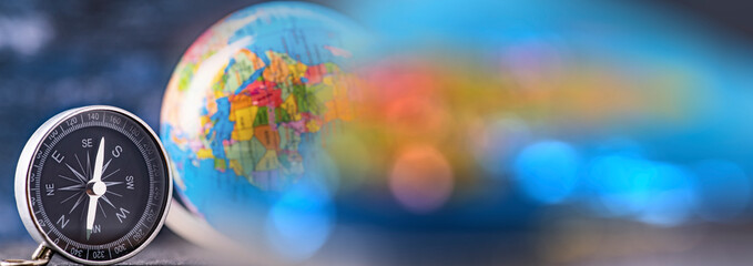 Travel planning navigation concept. Classic magnetic detail of compass on light blue with earth globe in the backround. Panorama, banner