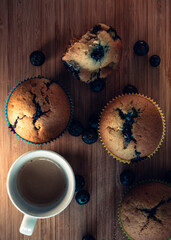 Top view of vegan blueberry muffins on a wooden board with a cup of coffee