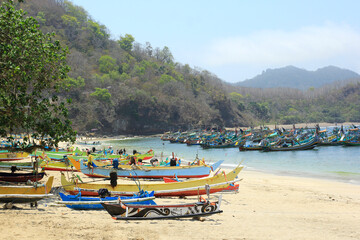 Fototapeta na wymiar Jember, Indonesia, Sept 12, 2015. The view of the traditional fishermen's boats leaning on the beach of Tanjung Papuma is very beautiful and colorful.