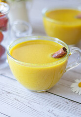 Golden vegan milk with turmeric powder and cinnamon. Close up of warm spicy comforting yellow color latte on wooden table. Healthy food concept.