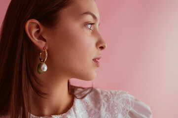 Elegant woman wearing trendy pearl earrings, posing on pink background. Copy, empty space for text