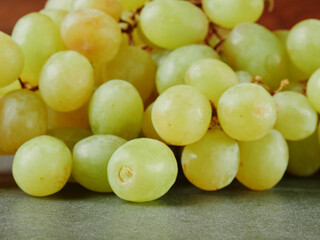 Multiple grape bunches on a wooden board against a dark background