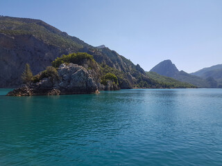 Fototapeta premium Seascape against the backdrop of mountains on a sunny, cloudless day.