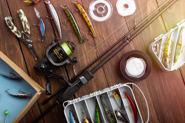 Fishing tackle - fishing spinning rod, hooks and lures on wooden background. Active hobby...