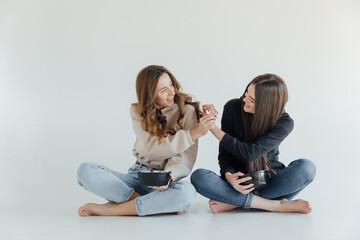 Two girl friends sitting on the floor and watch a movie and eat popcorn. Funny friends relaxing together.