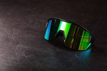 Sports glasses with a green mirrored lens and black frames on a black background