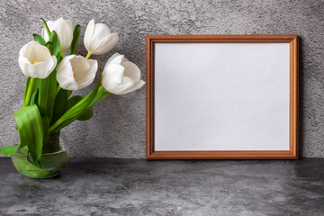 Portrait horizontal white picture frame mockup on vintage dark table with tulips jug vase grey concrete wall background.
