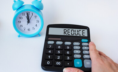 REDUCE, the text is written on the display of the calculator by a woman's hand. On white background