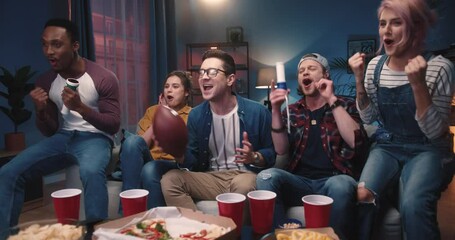 Multi-ethnic young male and female friends feeling excited emotionally cheering for soccer team and smiling when it score goal watching sport match on TV at home sitting on sofa, winning concept