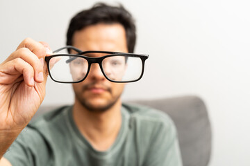 Foreground man showing dirty glasses. Blurry background. CloseUp at hands. Funny concept image.
