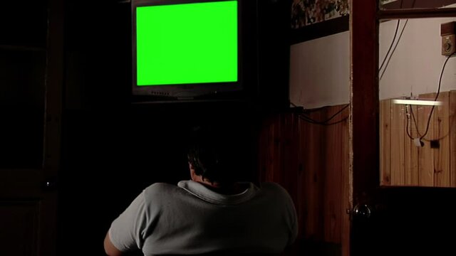 Man Watching Television Set with Green Screen in a Dark Room.  
You can replace green screen with the footage or picture you want. You can do it with “Keying” effect in After Effects.