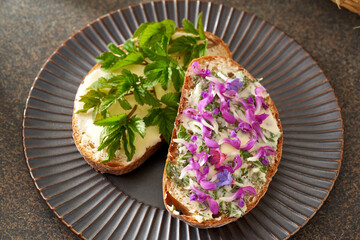 Two slices of bread with wild edible spring plants - goutweed leaves, purple dead-nettle and lungwort flo