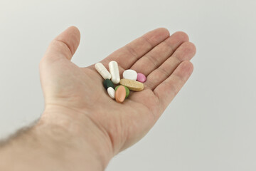 Hand full of a large heap of different multicolored pills