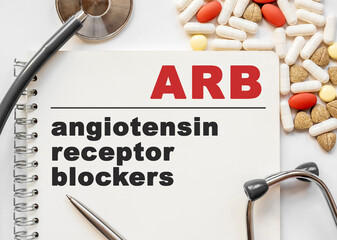 Page in notebook with ARB angiotensin receptor blockers on white background with stethoscope and group of pill. Medical concept. Term and abbreviation