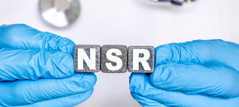 NSR Normal sinus rhythm of the heart - word from stone blocks with letters holding by a doctor's hands in medical protective gloves