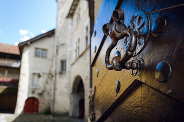 Ancient ring shaped metal knocker on a wooden studded door with signs of aging and weather