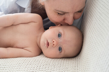 Attractive happy mother kiss lying with little baby boy. Happy family