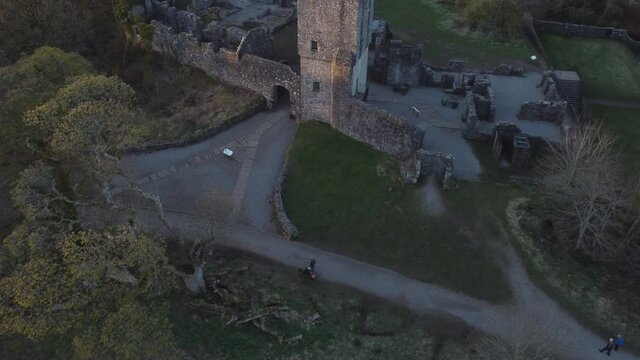 Low-level aerial footage over a castle ruin, lit by a low sun.