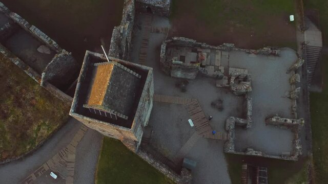 Ascending aerial footage over a castle ruin with square stone tower.