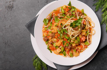 Caucasian lagman with meat, vegetables and homemade noodles, greens,  national home cooking