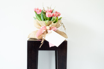 Blank paper greeting card, invitation. Bouquet of fresh pink tulips wrapped in burlap fabric...