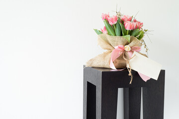 Blank paper greeting card, invitation. Bouquet of fresh pink tulips wrapped in burlap fabric...