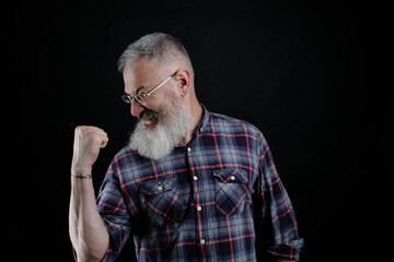 Portrait of happy joyful and emotive bearded mature european guy, raising fists high and yelling, triumphing or cheering while watching football match