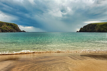 Irish beach with an incoming thunderstorm.
Sand, ocean and green mountains.