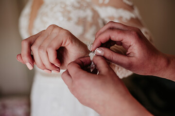 bride zipping buttoning her white wedding dress