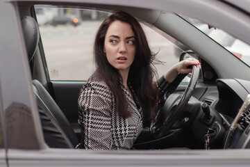 Fototapeta na wymiar portrait of attractive fabulous brunette woman wearing checkered dress in a lux car. lady in automobile.