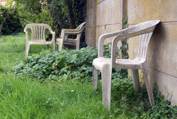 Old and damaged plastic chairs. Empty chairs in a garden.