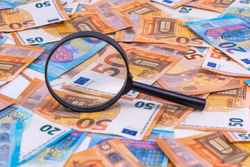 the magnifying glass lying on euro banknotes packground, close-up
