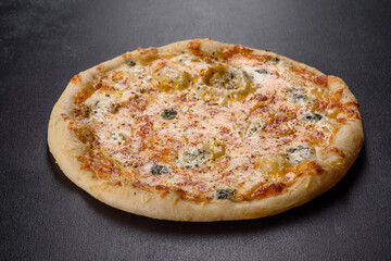 Tasty fresh oven pizza with tomatoes, cheese and mushrooms on a dark concrete background