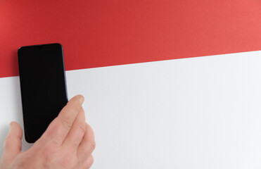 Hand with smartphone on red and white background. Red line