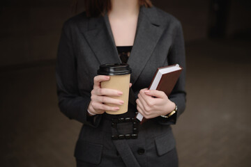 Young businesswoman with a notebook and coffee on the street.Close-up