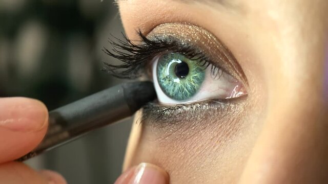 Close-up of beautiful, trendy makeup in green colors. MUA applies black eyeliner on the lower eyelid. High quality 4k footage