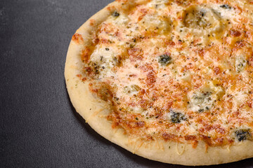 Tasty fresh oven pizza with tomatoes, cheese and mushrooms on a dark concrete background