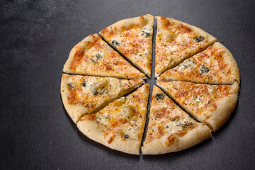 Tasty fresh oven pizza with tomatoes, cheese and mushrooms on a dark concrete background