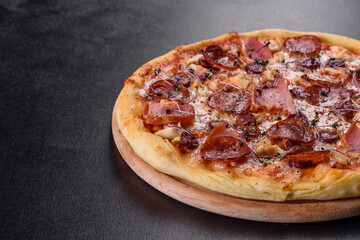 Delicious fresh oven pizza with tomatoes, salami and bacon on a dark concrete background