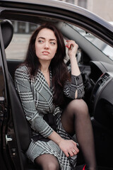 Fototapeta na wymiar portrait of attractive fabulous brunette woman wearing checkered dress in a lux car. lady in automobile.