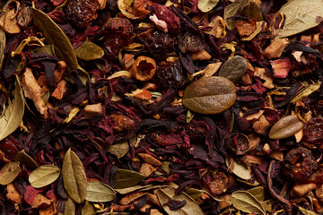 Tea leaves with hibiscus and fruits as background.