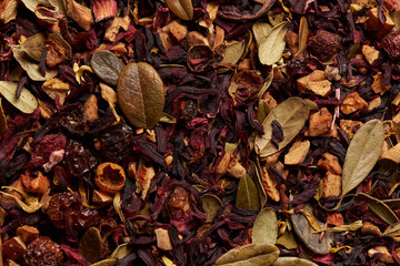 Dried tea leaves with hibiscus as a background.