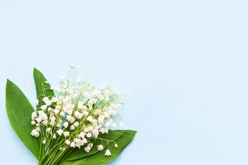 Gordijnen Bouquet of lily of the valleys on a blue background. View from above, copy space for text © Laima