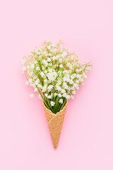 Bouquet of lily of the valleys in waffle ice cream cone on a pink background. Mothers Day, Valentines Day, bachelorette concept.